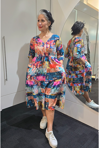 Woman wearing a colorful dress standing in front of a mirror. Tie Front Dress Turquoise