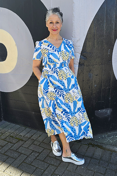 Woman in a blue and white patterned dress standing against a large letter 'O' on a wall.
V Neck Dress Blue