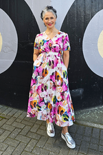 Woman wearing a colorful floral dress standing in front of a black and white wall.
V Neck Dress Pink