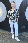 Woman in floral blouse and white pants standing in front of a black and gray wall.
V Neck Top Black