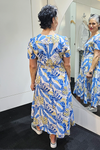 Woman trying on a blue and yellow patterned dress in front of a mirror.
V Neck Dress Blue