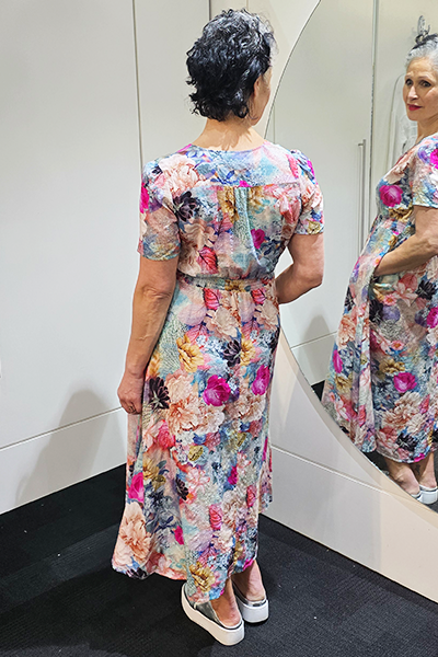 Woman wearing a colorful floral dress standing in front of a mirror.
V Neck Dress Multi
