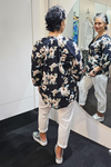 Person wearing a black floral shirt and white pants standing in front of a mirror.
V Neck Top Black