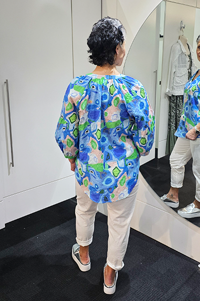 Person wearing a colorful patterned shirt in a store setting
V Neck Top Blue