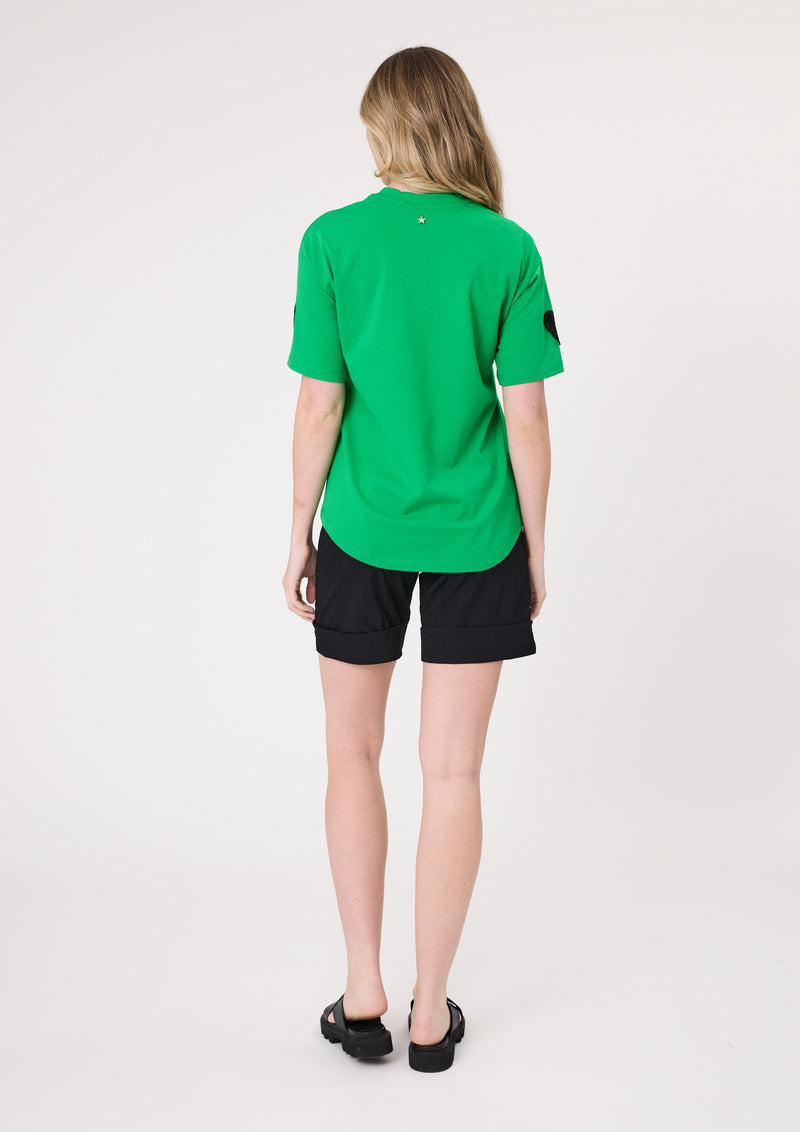 Person wearing a green shirt and black shorts on a white background
Valentina Tee Green