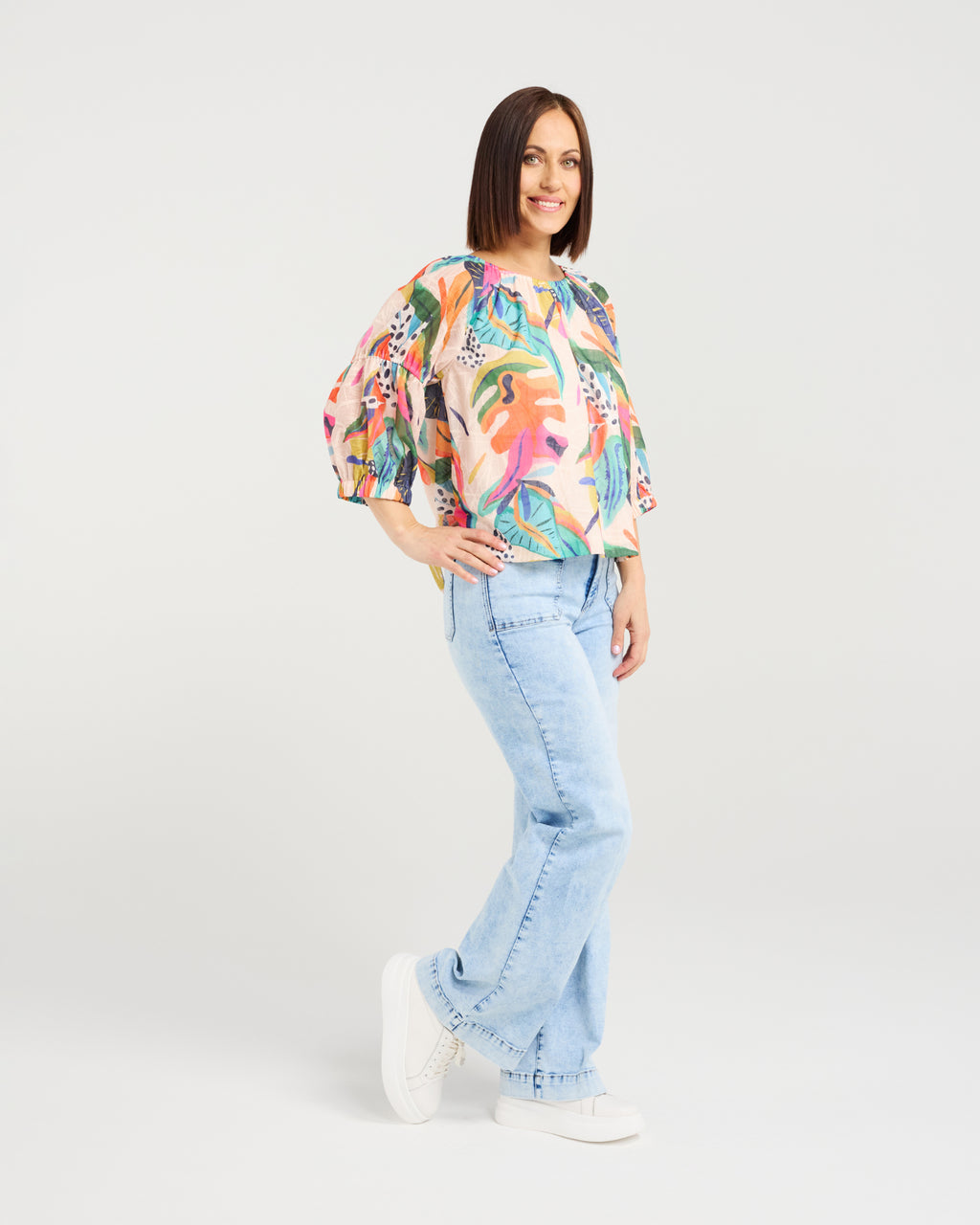 Woman wearing a colorful floral blouse and light blue jeans on a white background
Caitlin Top Vivid