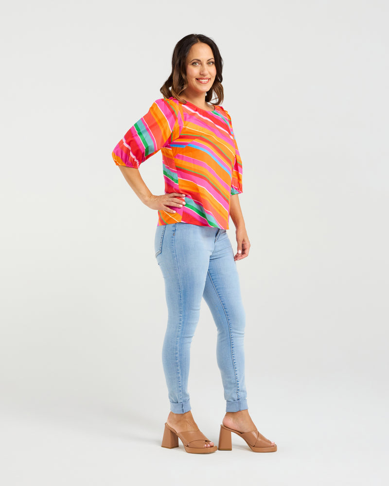 Woman wearing a colorful striped sweater and light blue jeans on a white background
Willow Top Dynamic Stripe