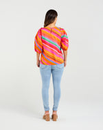Person wearing a colorful striped shirt and light blue jeans on a white background
Willow Top Dynamic Stripe
