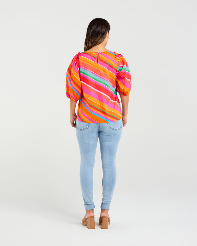 Person wearing a colorful striped shirt and light blue jeans on a white background
Willow Top Dynamic Stripe