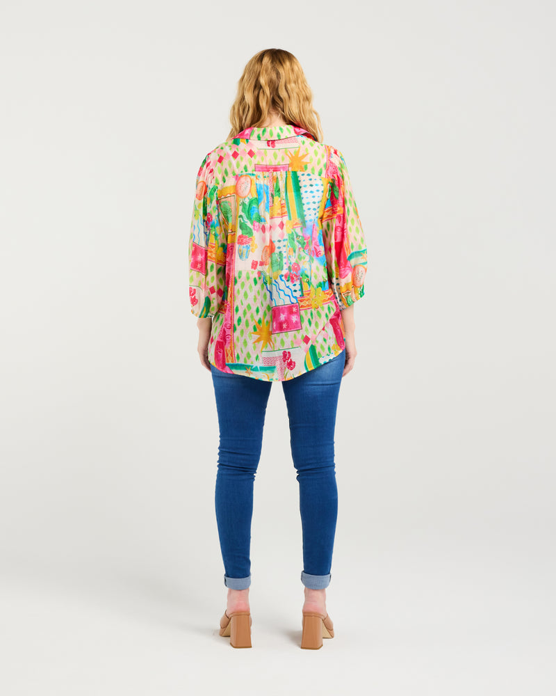 Woman wearing a colorful patterned shirt and blue jeans on a white background
Emily Shirt Radiant