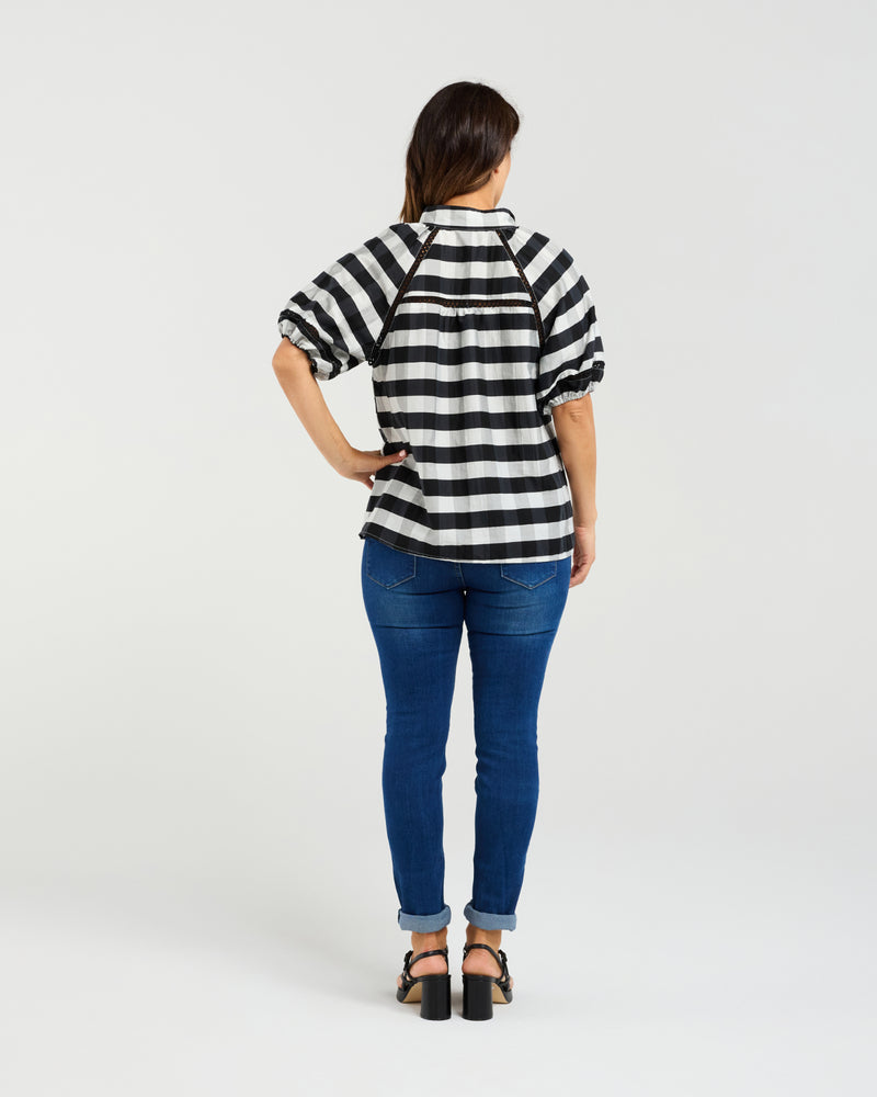 Person wearing a black and white striped shirt and blue jeans on a white background
Penelope Blouse Black Check