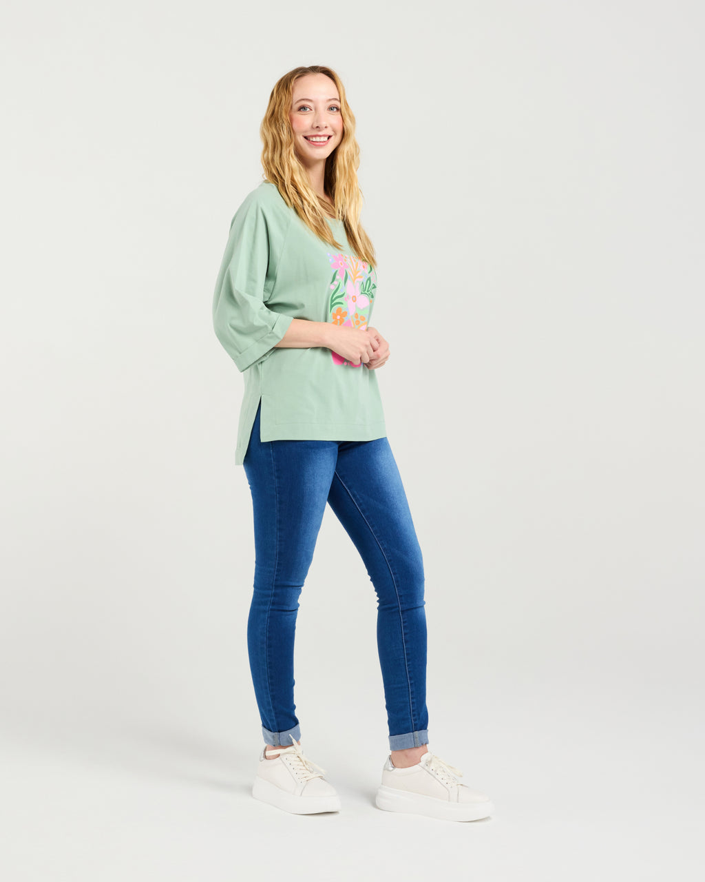 Woman wearing a light green sweater with a floral design and blue jeans on a white background
Kate T-Shirt Sage