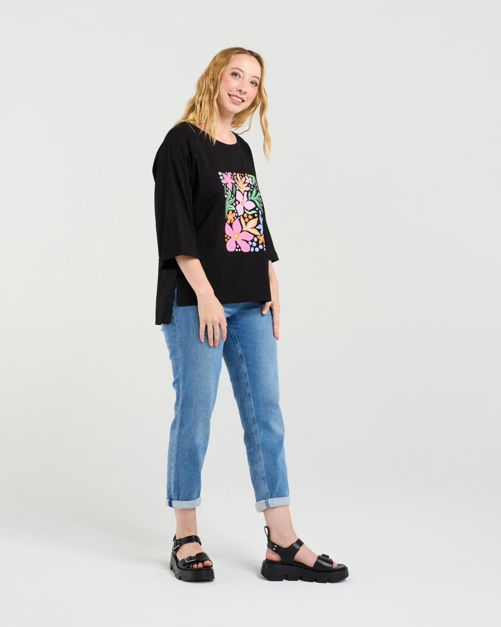 Woman wearing a black oversized t-shirt with colorful graphics and blue jeans on a white background
Kate T-Shirt Black