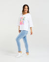 Woman wearing a white t-shirt with a colorful graphic and light blue jeans on a white background
Kate T-Shirt White