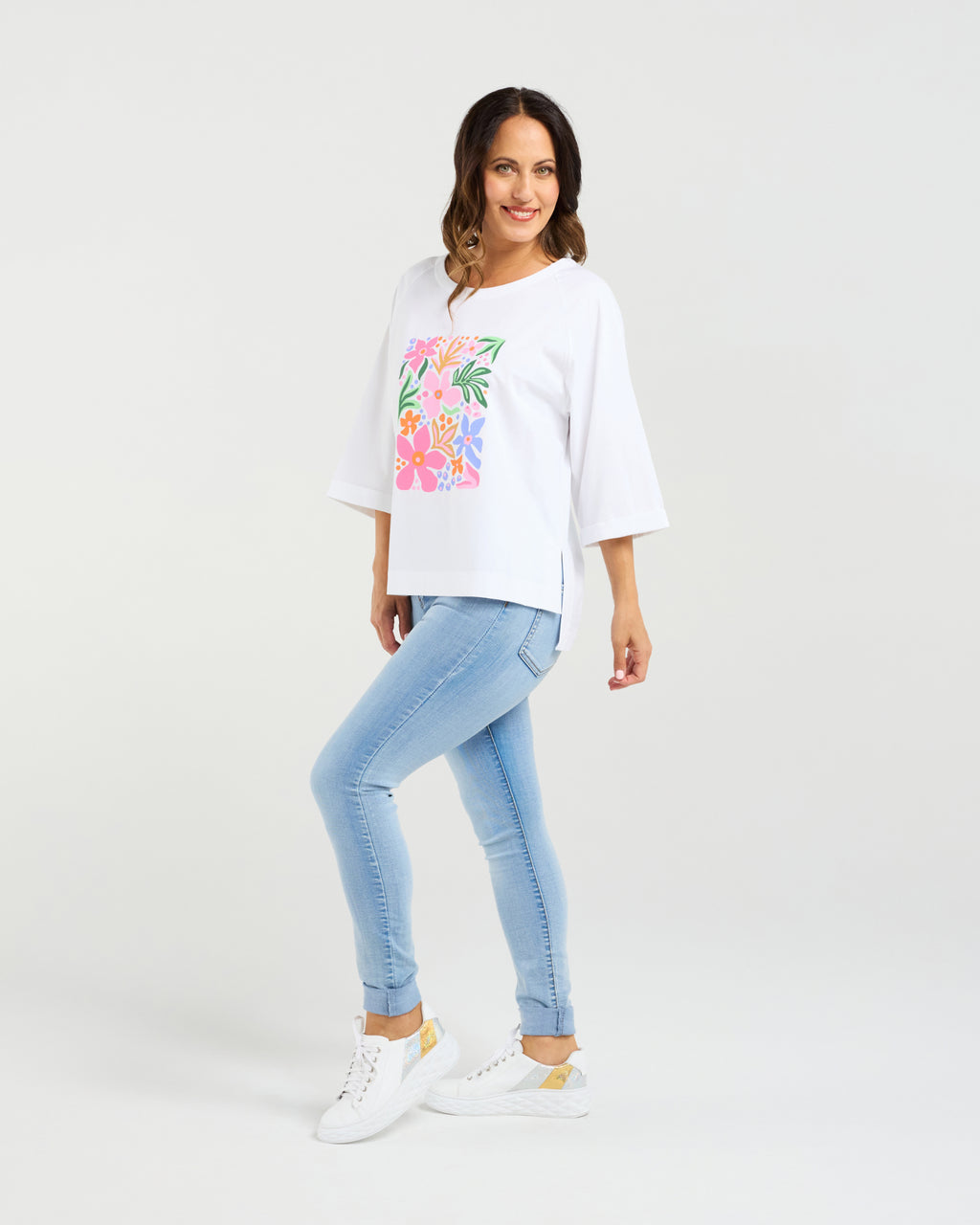 Woman wearing a white t-shirt with a colorful graphic and light blue jeans on a white background
Kate T-Shirt White