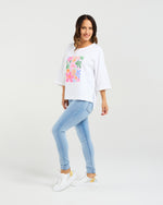 Woman wearing a white t-shirt with a colorful graphic and light blue jeans on a white background
Kate T-Shirt White