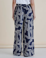 Navy blue pants with white geometric pattern worn by a person on a beige background
