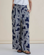 Person wearing navy blue pants with white geometric pattern on a beige background