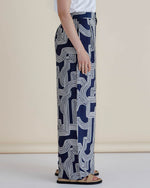 Person wearing navy blue pants with white geometric pattern on a beige background