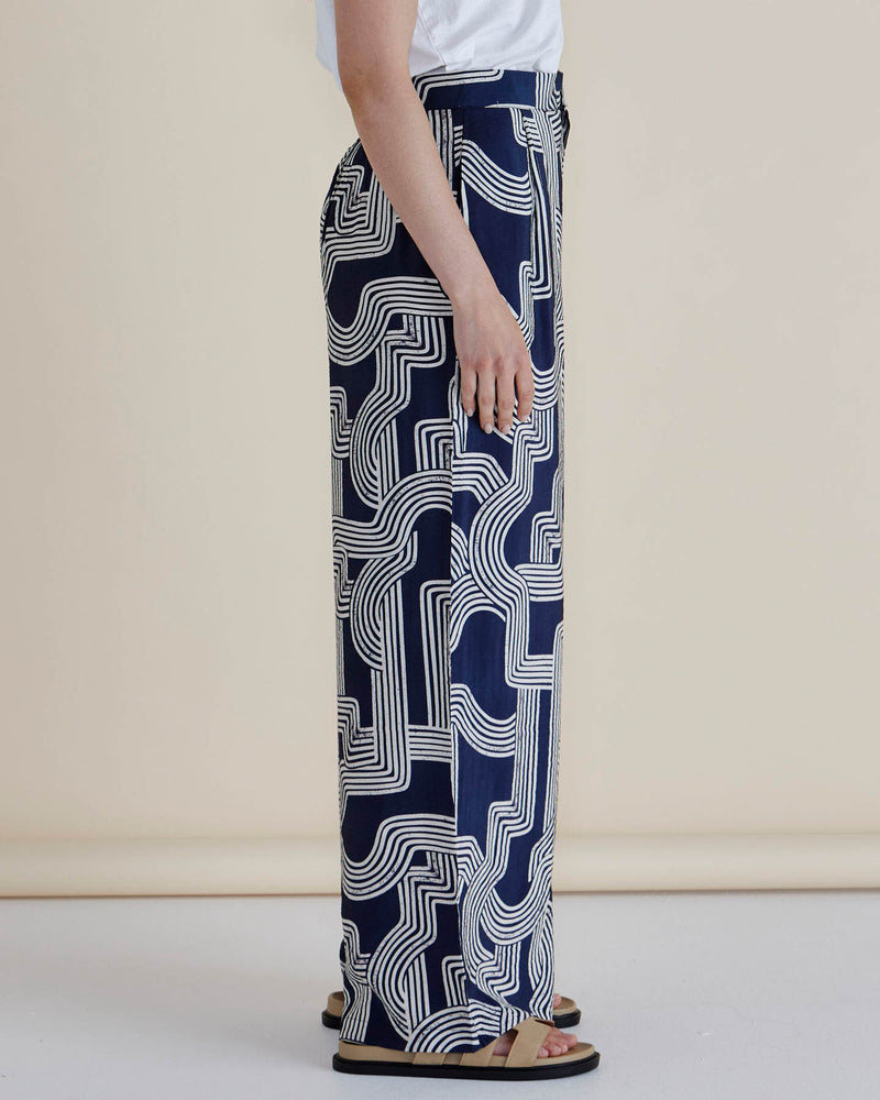 Person wearing navy blue pants with white geometric pattern on a beige background