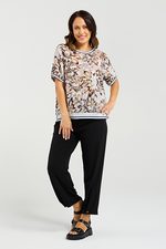 Woman wearing a floral blouse and black pants on a white background Zoe Top Sage Mosaic