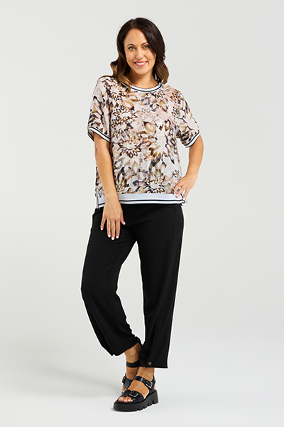 Woman wearing a floral blouse and black pants on a white background Zoe Top Sage Mosaic