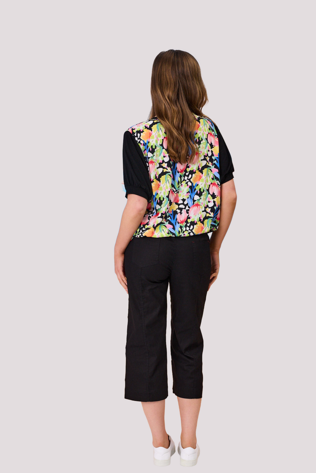 Woman wearing a colorful floral vest over a black shirt and black pants on a white background Chloe Top Black