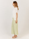 Woman wearing a white top and light green pants on a plain background Corsica knit White
