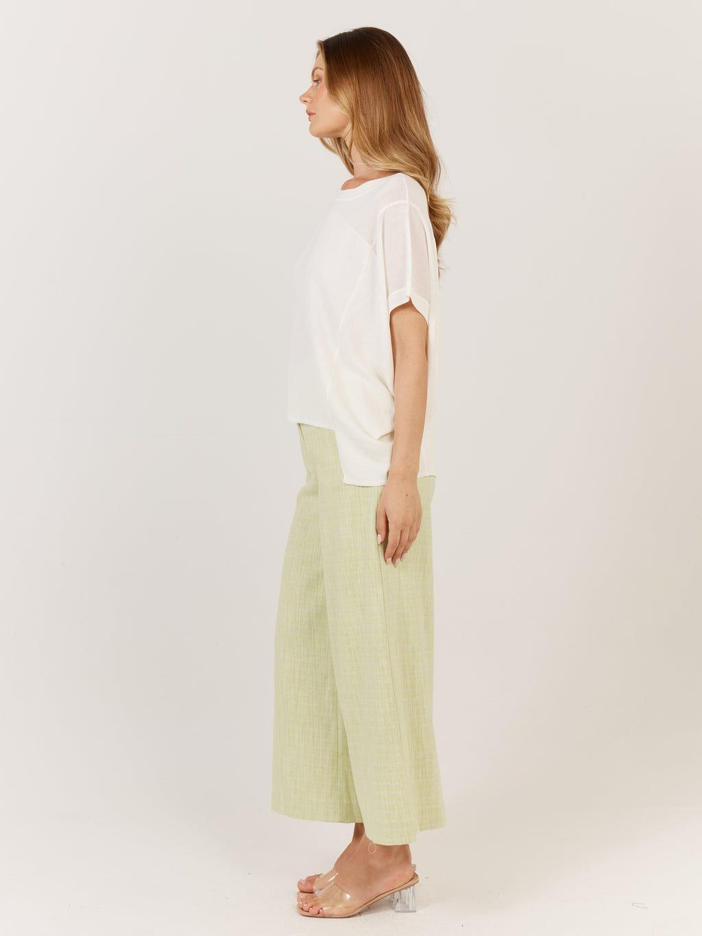 Woman wearing a white top and light green pants on a plain background Corsica knit White