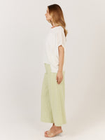 Woman wearing a white top and light green pants on a plain background Corsica knit White