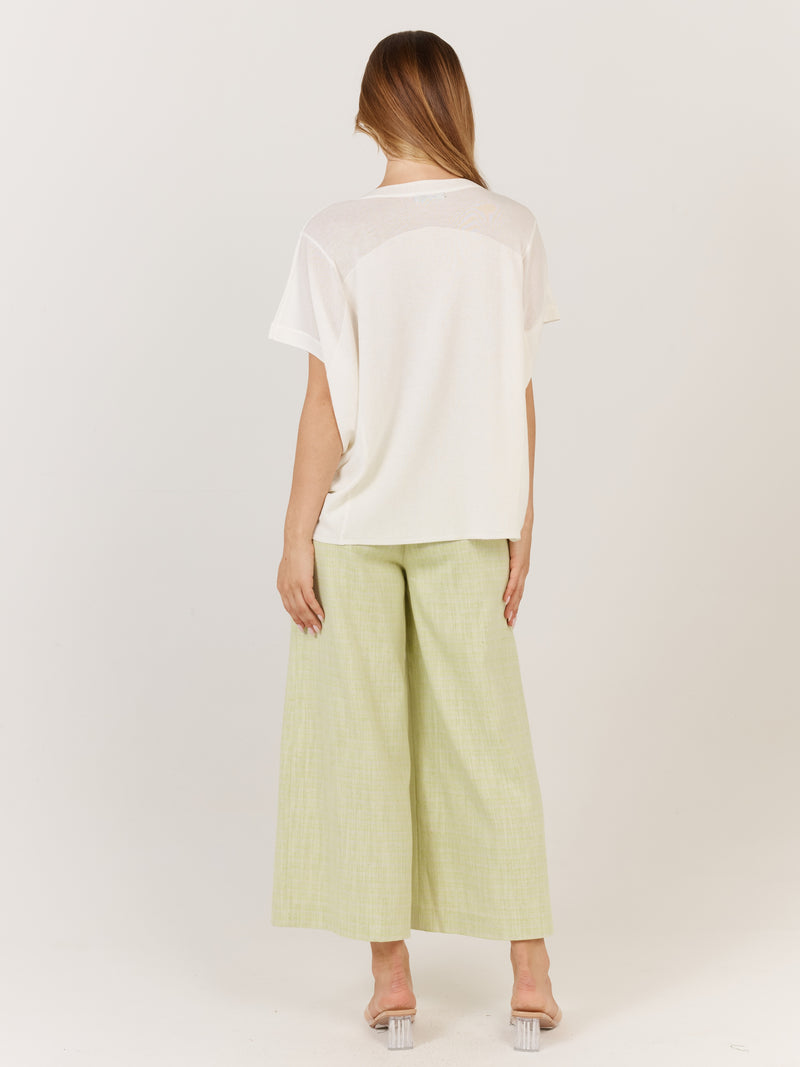 Person wearing a white top and light green pants on a plain background Corsica knit White