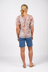 Woman wearing a patterned top and blue shorts on a white background